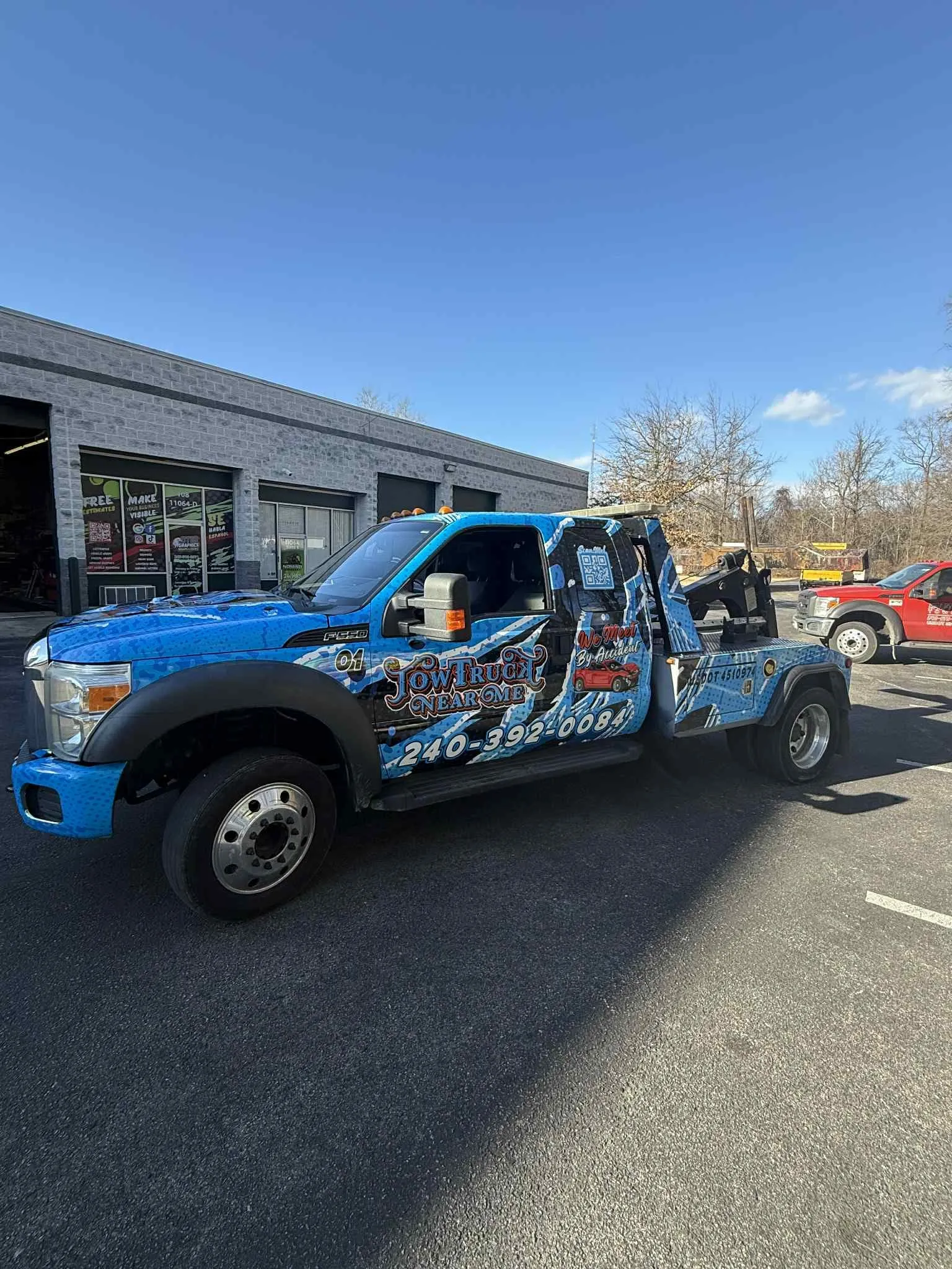 Flatbed tow truck with blue vehicle wrap, shop interior